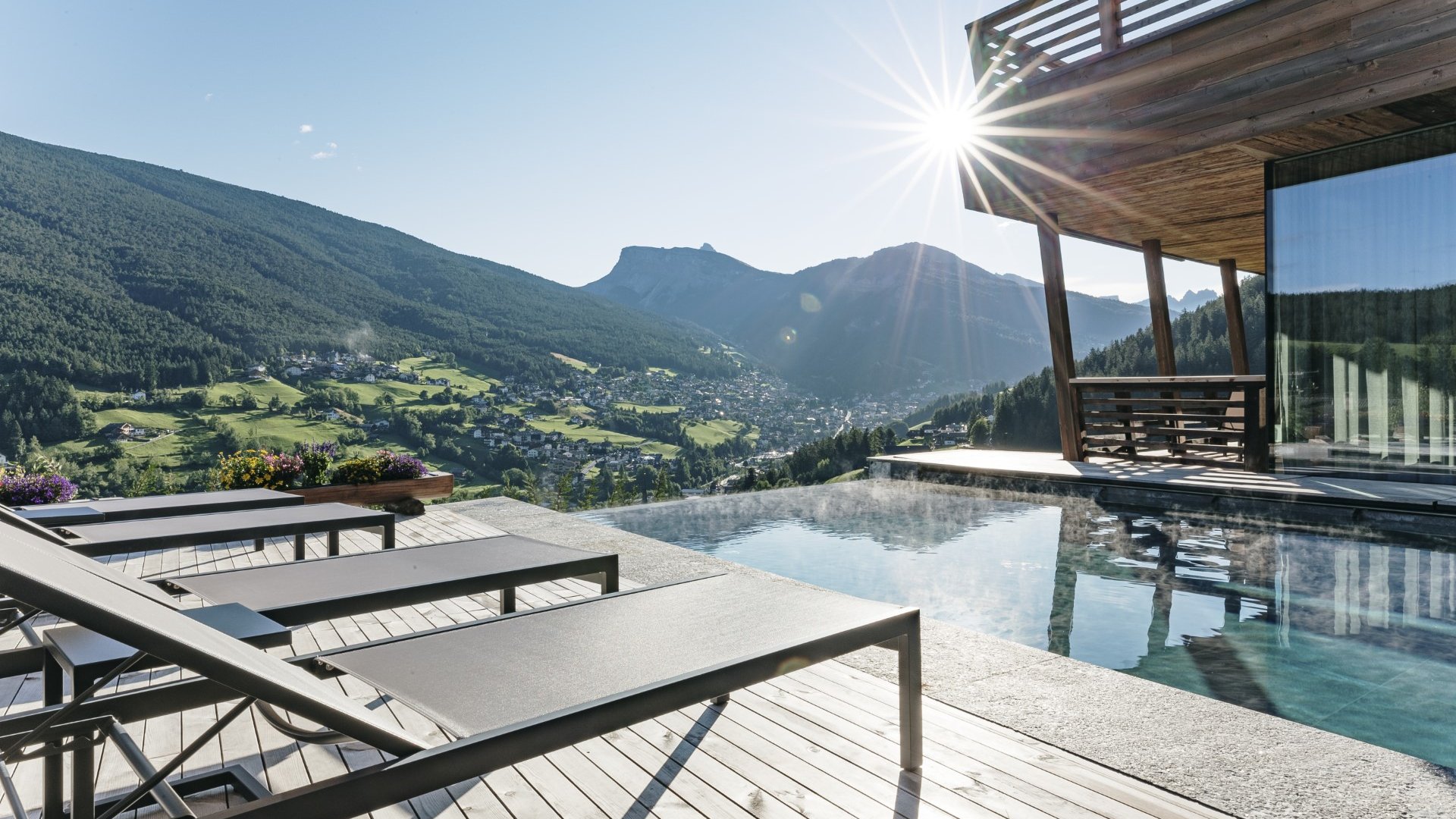 Sonnenlicht über beheiztem Pool mit Liegestühlen und Bergblick